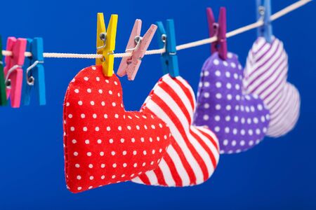 hearts hanging on a clothesline with clothespins, focus on red  Blue backgroundの写真素材