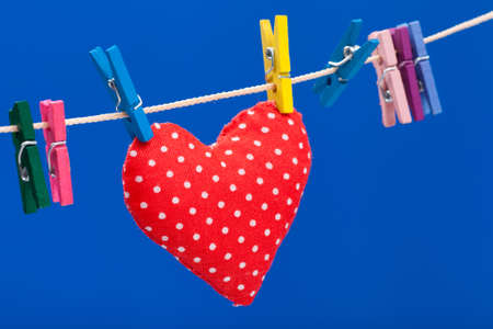 red heart hanging on a clothesline with clothespins, blue backgroundの写真素材