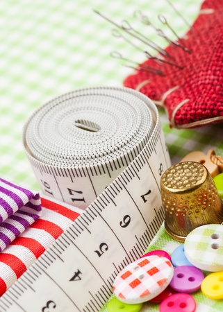 Sewing items: buttons, colorful fabrics, measuring tape, pin cushion, thimble  の写真素材