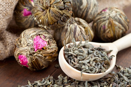 Green tea balls with flowers and wooden spoon with tea on kitchen tableの写真素材