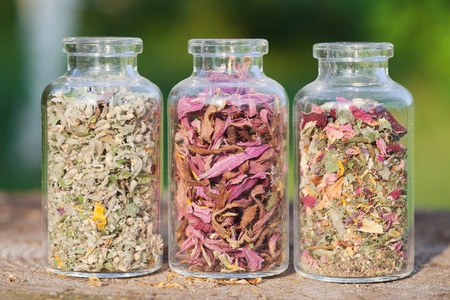glass bottles with healing herbs on wooden board in sunset sunlight, herbal medicineの写真素材