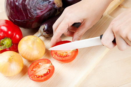 Womens hands with a knife cut vegetables on cutting boardの写真素材