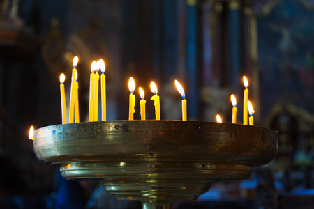 Several tall candles lit in a dark room in churchの写真素材