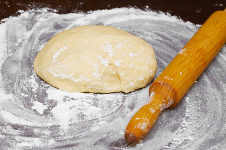 dough and wooden rolling pin on tableの写真素材