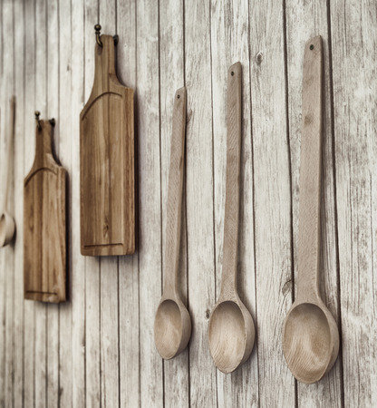 Vintage stylized photo of cutting boards and wooden spoons hanging on the wall, kitchen utensilsの写真素材