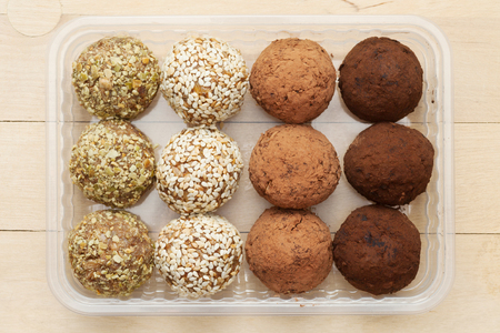macrobiotic healthy food: balls from ground wheat sprouts with sesame, pumpkin seeds and chocolate sprinkles in plastic boxの写真素材