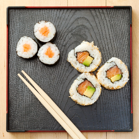 sushi rolls assortment on black plate and wooden chopsticks, top viewの写真素材