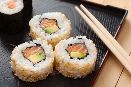 sushi rolls assortment on black plate and wooden chopsticksの写真素材