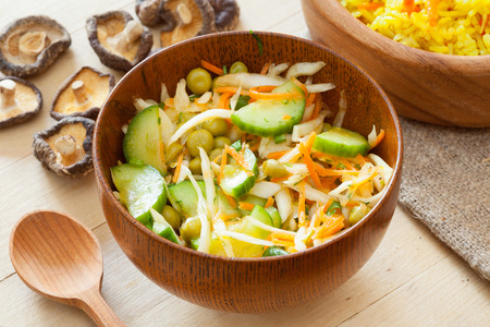 vegetable salad in rustic wooden bowl on kitchen tableの写真素材