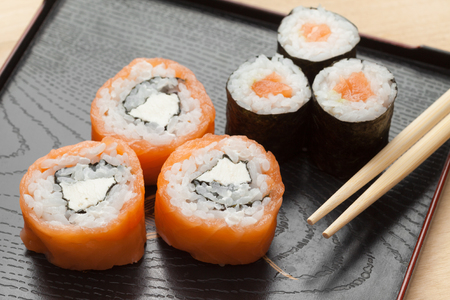 Sushi of smoked Salmon and Philadelphia cheese and maki with chopsticksの写真素材