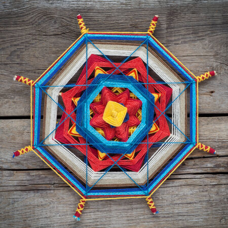Knitted tibetan mandala from threads on old wooden plank, top viewの写真素材