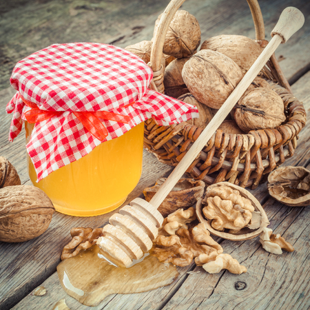 Honey in jar, walnut in basket and wooden dipper on old kitchen tableの写真素材