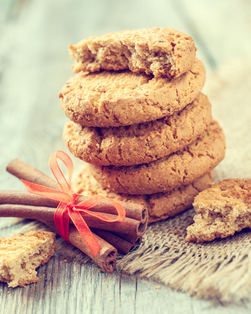 homemade oat cookies and cinnamon sticks on old tableの写真素材