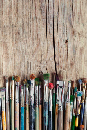 row of artist paintbrushes on old wooden rustic tableの写真素材