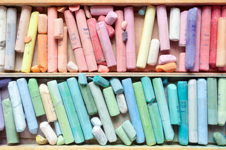 Pastel crayons in wooden artistic box closeup, top view.