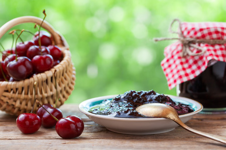 Basket with cherry, saucer and  jar of jam.の写真素材