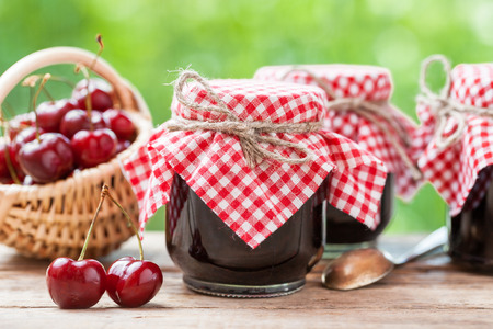 Jars of jam and basket with cherry.の写真素材
