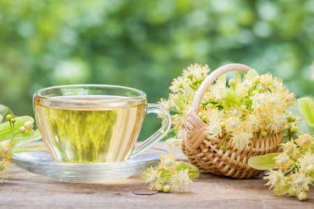 Cup of healthy linden tea and wicker basket with lime flowers, herbal medicine.の写真素材