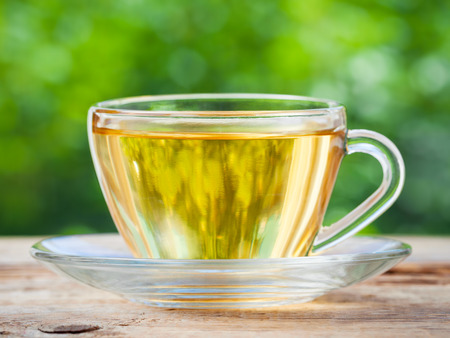 Tea cup on wooden table. Green background.の写真素材