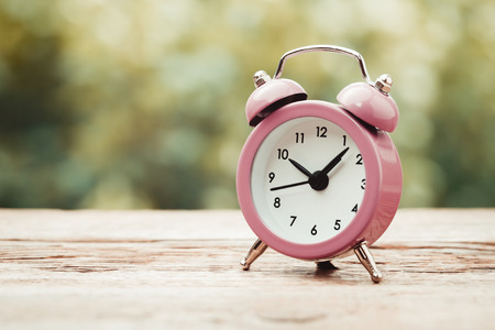Vintage stylized photo of alarm clock on wooden tableの写真素材