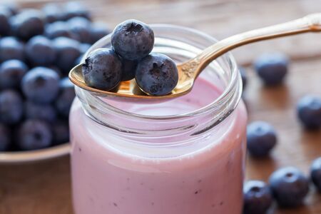 Fresh blueberries yogurt in glass jar and spoonの写真素材