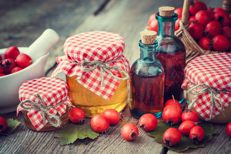 Jars of honey, tincture bottles and mortar of hawthorn berries on table. Herbal medicine. Selective focus.の写真素材