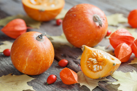 Pumpkins on old wooden table with maple leaves. Autumn still life.の写真素材