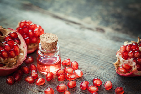 Pomegranate oil in bottle and garnet fruit with seeds on table. Selective focus.の写真素材