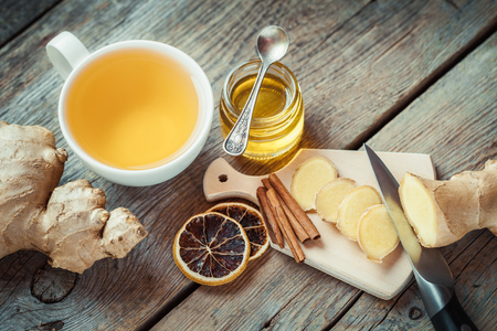 Ginger on cutting board, jar of honey, tea cup on kitchen table. Top view.の写真素材