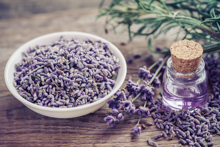 Bottle of essential oil and lavender flowers in bowl and on table. Selective focus.の写真素材