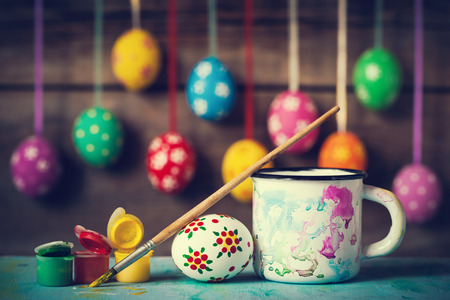 Painting Easter eggs and hanging colorful eggs on rustic wooden backgroundの写真素材