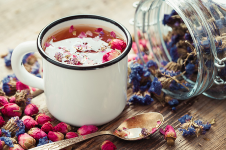 Rose buds tea in tea cup and glass jar of forget me not flowers. Retro toned.の写真素材