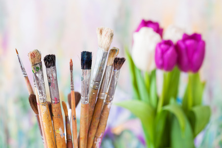 Artistic paintbrushes, bouquet of tulips and painting on backgroundの写真素材