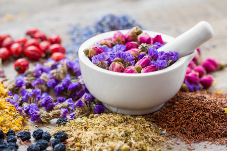 Mortar of healing herbs, herbal tea assortment and dry berries on table. Herbal medicine.の写真素材