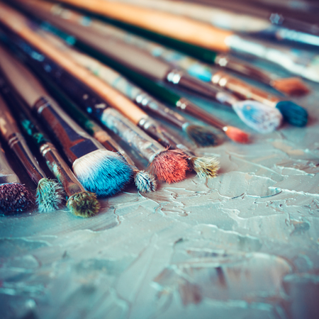 Artistic paintbrushes on artist canvas covered with oil paints