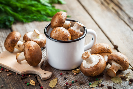 Mushrooms in enameled mug, dill and spices on wooden table.の写真素材