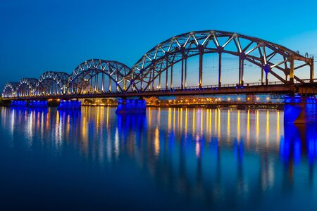 Illuminated railway bridge at twilight in Riga, Latviaの写真素材