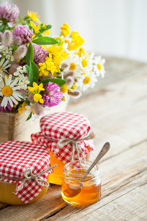 Jars of honey and summer healing herbs bunch on table. Selective focus.の写真素材
