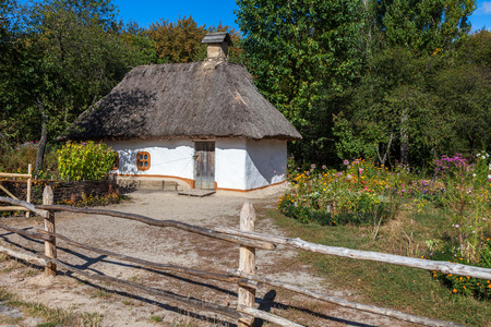 Retro ukrainian cottage with thatched roof and garden in Pirogovo village, Kiev region, Ukraine.の写真素材