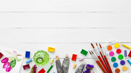 Watercolor paints, brushes for painting, pencils and crayons on white table. Top view. Flat lay.の写真素材