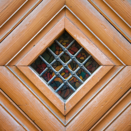 Vintage door spyhole with stained glass window and grid in an old door of wood.の写真素材