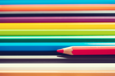 Background of pencils in different colors and red pencil in foreground.の写真素材