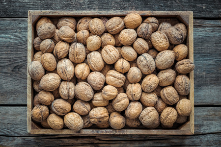 Walnuts in wooden box on old table, top view. Retro toned.の写真素材