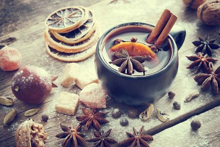 Mulled wine in black mug and ingredients on table. Retro toned.の写真素材