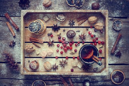 Mulled wine in black mug with spices and ingredients in wooden box. Top view, flat lay. Retro toned photo.の写真素材