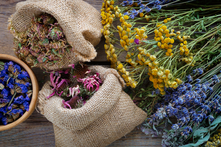 Medicinal herbs, wooden mortar and two bags of dry healthy flowers on wooden table. Herbal medicine. Top view, flat lay.の写真素材