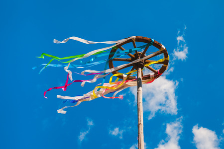 Wooden wheel with colorful ribbons on blue sky background. Slavic celebration of Midsummerの写真素材