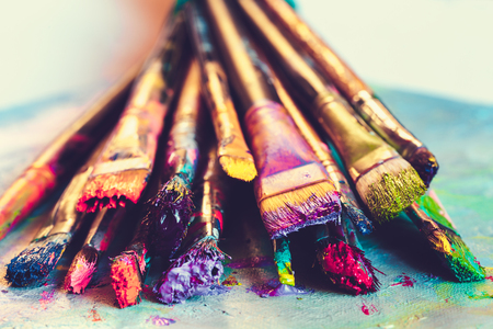 Artist paintbrushes with paint closeup on artistic canvas. Retro toned. Selective focus.の写真素材