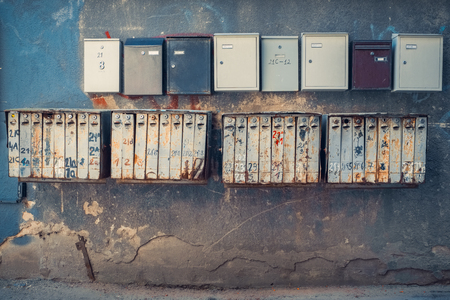 Rows of retro rusty and modern mailboxes on old wall.の写真素材
