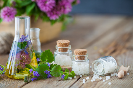 Vials of tincture or infusion of healthy herbs, bottles of homeopathy globules and healthy herbs on table. Alternative medicine concept.の写真素材